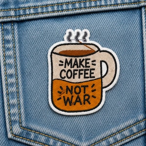 May include: An embroidered patch shaped like a coffee mug with a white border, featuring a beige top half and an orange bottom half. The text "MAKE COFFEE" is in black on the beige section, and "NOT WAR" is in black on the orange section.