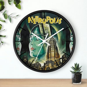 May include: A black and white clock with a vintage movie poster design featuring a woman's face and the word "Metropolis".