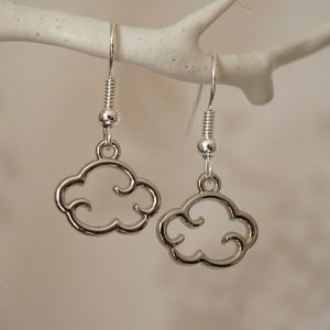 May include: Silver cloud shaped dangle earrings with a simple design. The earrings are hanging from a white branch.