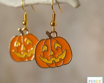 May include: A pair of gold-colored Halloween earrings featuring orange pumpkin faces with yellow highlights. The earrings are hanging from a white branch. The text "FUNKY EARRINGS UK" is in the bottom right corner.
