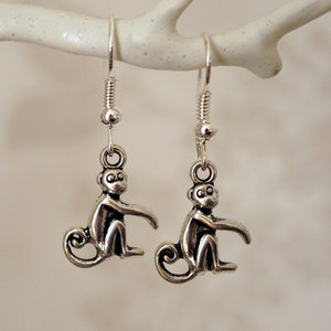 May include: Silver monkey dangle earrings with a simple hook closure.