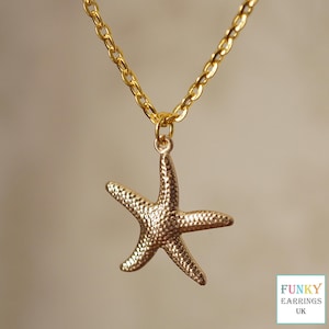 May include: A gold chain necklace with a gold starfish pendant. The starfish has a textured surface.