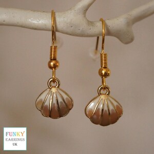May include: Gold tone earrings with a white and pink seashell design.