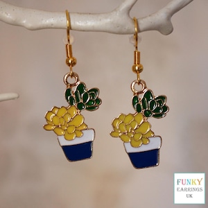 May include: Gold dangle earrings featuring a yellow succulent plant in a blue and white pot.