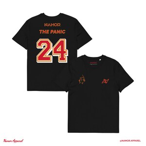 Può includere: T-shirt nere con la scritta "NAMOR THE PANIC 24" in rosso e bianco sul retro. Una maglietta ha una piccola grafica arancione e la scritta "NAMOR" sul davanti. L'altra maglietta ha una grafica arancione e la scritta "NAMOR" sul davanti.
