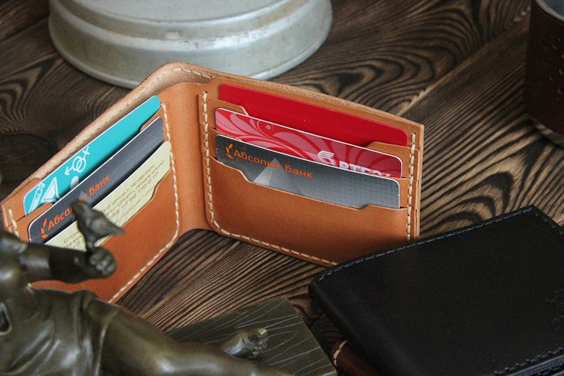 May include: A brown leather wallet with multiple card slots, showing a few cards with the text "Абсолют Банк" in Cyrillic script.