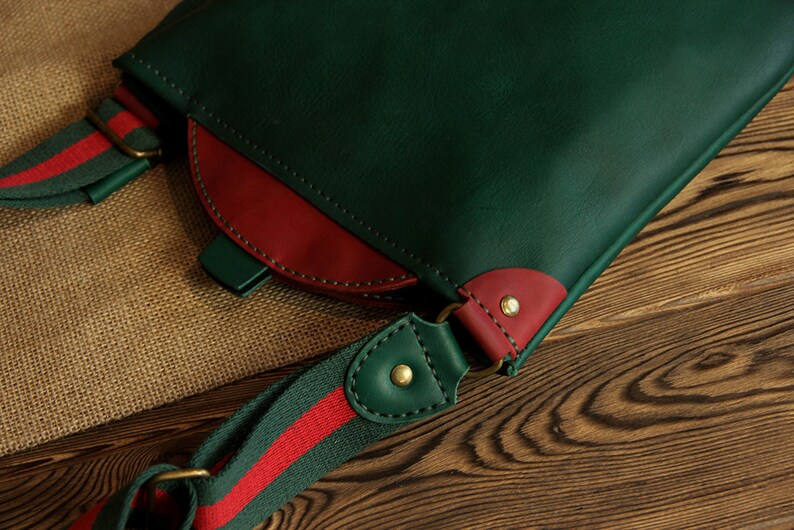 May include: A green leather crossbody bag with a red leather accent and a green and red striped strap.
