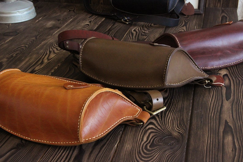 May include: Three leather bags in different shades of brown. The bags are all made of a soft, supple leather and have a simple, classic design. The bags are all closed with a buckle.