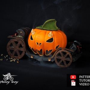 Peut inclure: Une citrouille sculptée avec un chapeau vert est placée dans un petit chariot en cuir noir avec des roues. La citrouille a un visage effrayant avec un large sourire et des dents pointues. Le chariot est décoré d'accents dorés et possède un petit sac en cuir noir sur le côté. L'arrière-plan est noir.