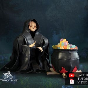 Peut inclure: Scène d'Halloween avec une figurine en robe noire à capuche et masque de crâne, à côté d'un chaudron noir rempli de bonbons colorés. Le chaudron repose sur une base en bois avec des flammes rouges.