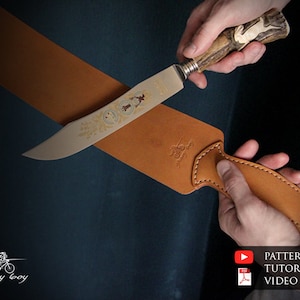 Peut inclure: Un fourreau en cuir brun avec un bord cousu et un motif décoratif. Un couteau de chasse avec un manche en bois de cerf et une lame détaillée est placé dans le fourreau.