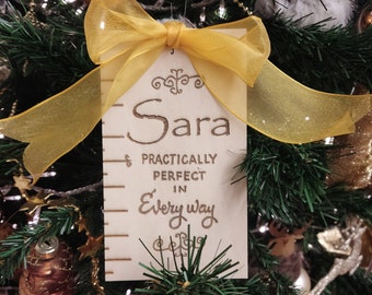 May include: A wooden Christmas ornament with a yellow ribbon and the text "Sara Practically Perfect in Every Way".
