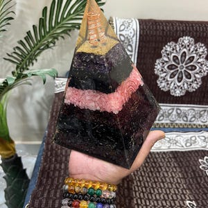 Puede incluir: Una gran pir&aacute;mide de cristal multicolor con una bobina de alambre de cobre en su interior. La pir&aacute;mide est&aacute; hecha de amatista, cuarzo rosa y obsidiana negra.