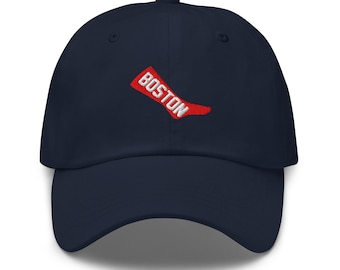 May include: A navy blue baseball cap with a curved peak. The cap displays the word "BOSTON" in white, edged in red, embroidered on the front. The hat has a classic six-panel design with a button on top.