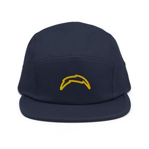 Peut inclure: Une casquette 5 panneaux bleu marine avec un logo brodé jaune en forme d'arc de cercle représentant un éclair.