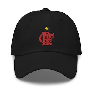 Op de afbeelding: Zwarte baseballpet met een rood geborduurd logo met een gestileerd "CRF"-ontwerp en een gele ster erboven. De pet heeft een gebogen klep en een stoffen bandsluiting.