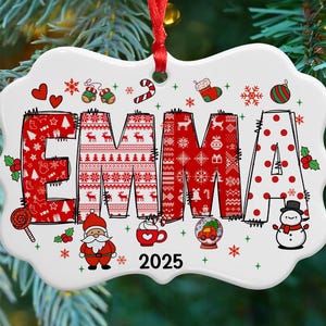May include: A white ceramic Christmas ornament with the name "EMMA" in red and white festive patterns. The ornament includes holiday-themed illustrations like Santa, snowflakes, and a snowman, with the year "2025" displayed.