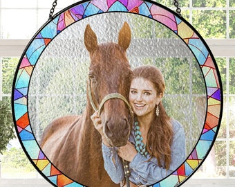 May include: A stained glass window hanging with a colorful geometric border. The window features a photo of a woman and a horse.