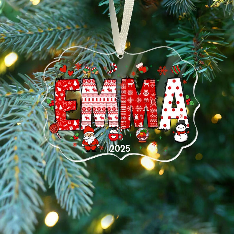 May include: A clear, rectangular Christmas ornament with the name "EMMA" in red and white festive patterns. The year "2025" is printed below the name, along with holiday-themed illustrations like Santa, a snowman, and candy canes.
