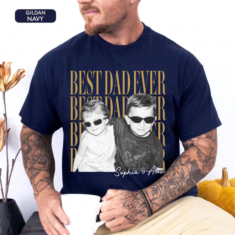 Pode incluir: Camiseta azul marinho com a frase dourada "BEST DAD EVER". Apresenta uma foto em preto e branco de duas crian&ccedil;as usando &oacute;culos de sol, com os nomes "Sophia & Alex" impressos abaixo.