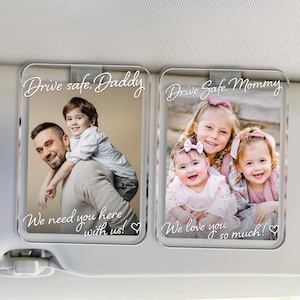 May include: Two clear acrylic car visor clips with family photos. One clip reads "Drive safe, Daddy" and "We need you here with us!" The other reads "Drive Safe, Mommy" and "We love you so much!"