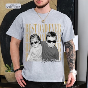 Pode incluir: Camiseta cinza claro com a frase dourada "BEST DAD EVER". Apresenta uma foto em preto e branco de duas crian&ccedil;as usando &oacute;culos de sol. Os nomes "Sophia & James" est&atilde;o escritos abaixo.