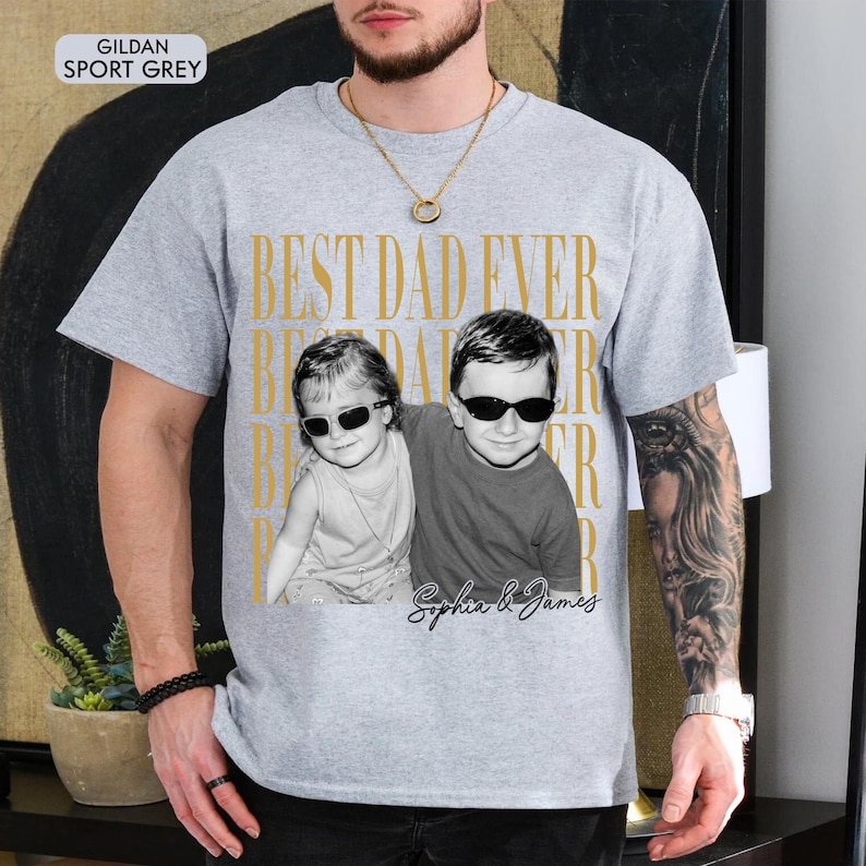 Pode incluir: Camiseta cinza claro com a frase dourada "BEST DAD EVER". Apresenta uma foto em preto e branco de duas crian&ccedil;as usando &oacute;culos de sol. Os nomes "Sophia & James" est&atilde;o escritos abaixo.