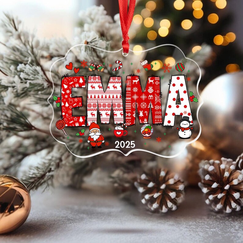 May include: A clear, rectangular Christmas ornament with the name "EMMA" in red, decorated with holiday patterns and icons. The year "2025" is printed below. A red ribbon is attached for hanging. Festive holiday decor.