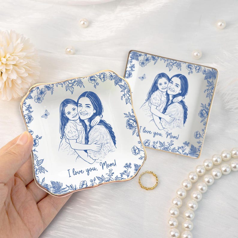Puede incluir: Dos platos cuadrados de cer&aacute;mica con dise&ntilde;os florales azules y bordes dorados. Cada plato presenta un dibujo lineal azul de una madre y un ni&ntilde;o con el texto "I love you, Mom!".