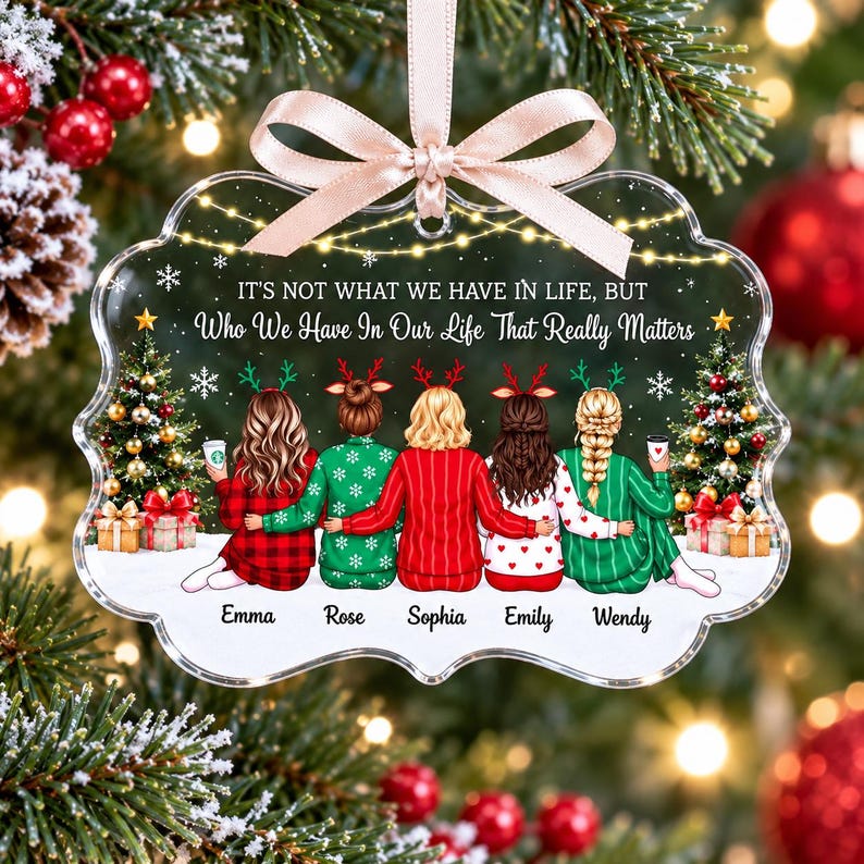 May include: A clear, scalloped-edge acrylic Christmas ornament featuring a printed illustration of five people from behind, wearing holiday pajamas and reindeer headbands. The text reads: IT'S NOT WHAT WE HAVE IN LIFE, BUT WHO WE HAVE IN OUR LIFE THAT REALLY MATTERS. Names Emma, Rose, Sophia, Emily, and Wendy are printed below.