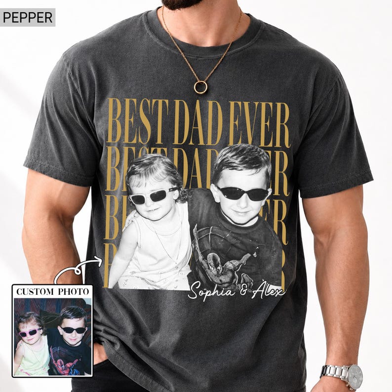 Pode incluir: T-shirt cinza escuro com foto personalizada e o texto dourado "BEST DAD EVER". A foto mostra duas crian&ccedil;as usando &oacute;culos de sol. A camisa tamb&eacute;m tem o texto "Sophia & Alex".