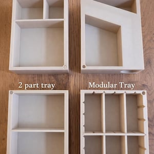 May include: Four wooden trays are shown, each with a unique design. The trays include a 3-part tray, a dice tower tray, a 2-part tray, and a modular tray. The text "3 part tray", "Dice tower tray", "2 part tray", and "Modular Tray" are visible.