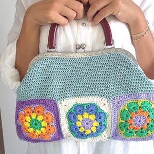 The bag is finished with a sturdy metal kiss lock clasp and elegant dark handles, making it perfect for both casual outings and special occasions.