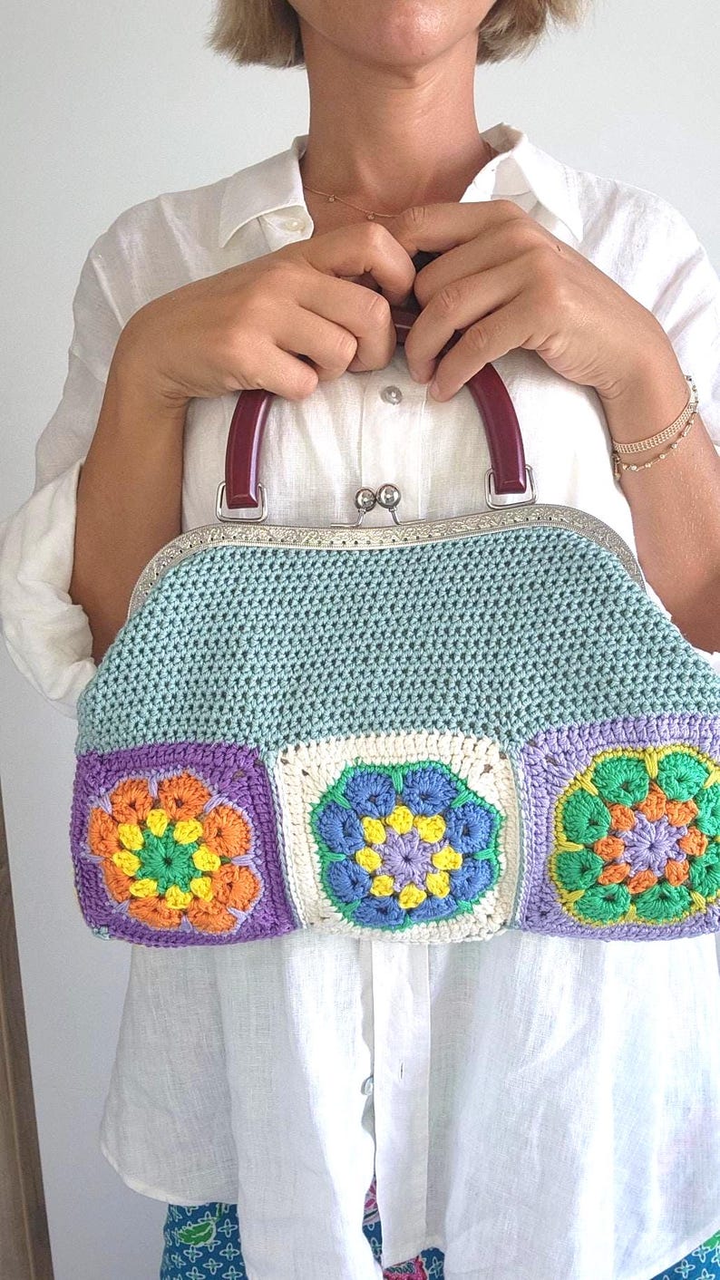 The bag is finished with a sturdy metal kiss lock clasp and elegant dark handles, making it perfect for both casual outings and special occasions.