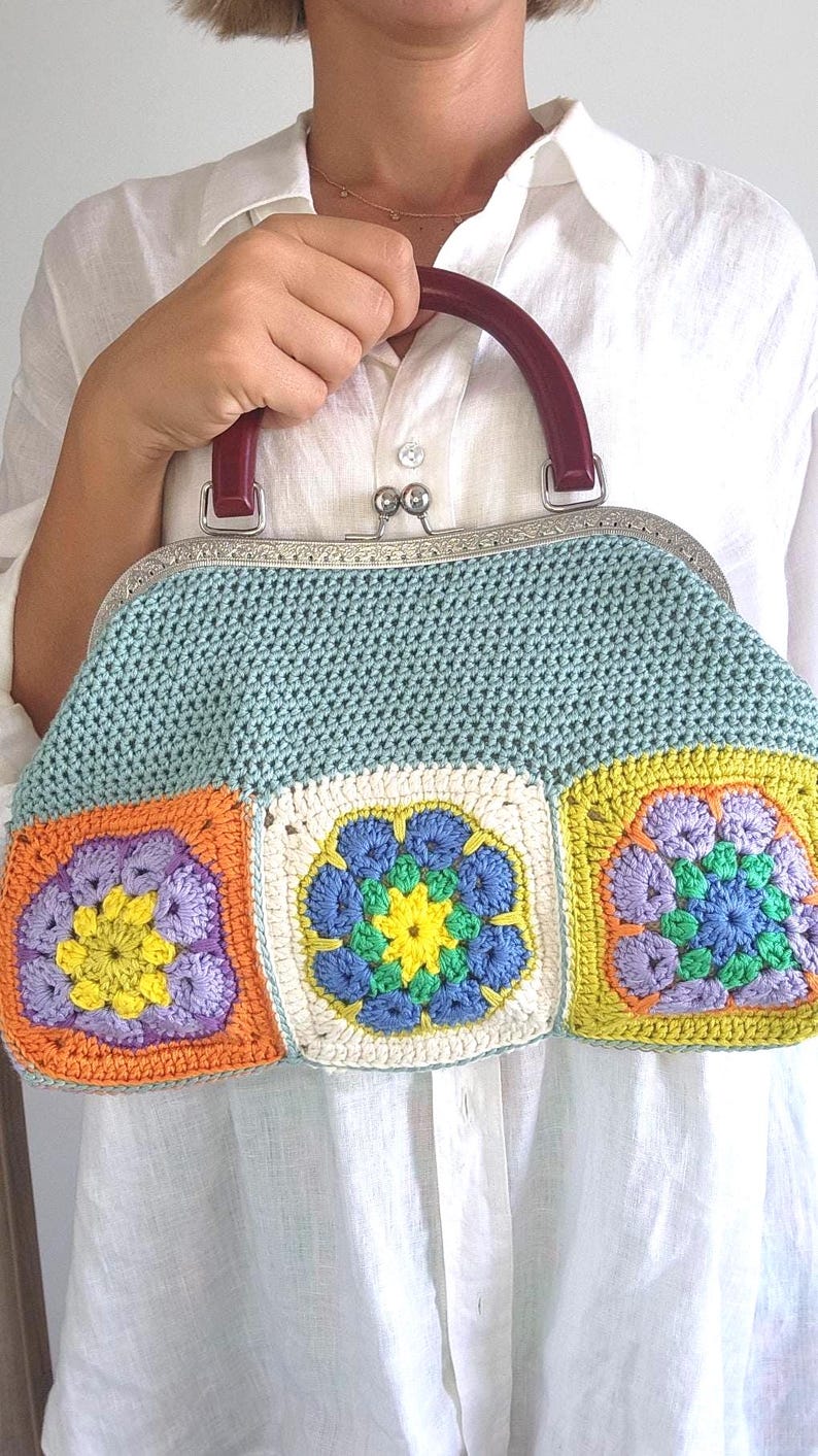 Made with 100% cotton yarn, this unique frame bag features colorful granny square motifs on both sides, creating a bold and playful look.