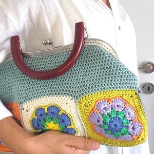 The bag is finished with a sturdy metal kiss lock clasp and elegant dark handles, making it perfect for both casual outings and special occasions.