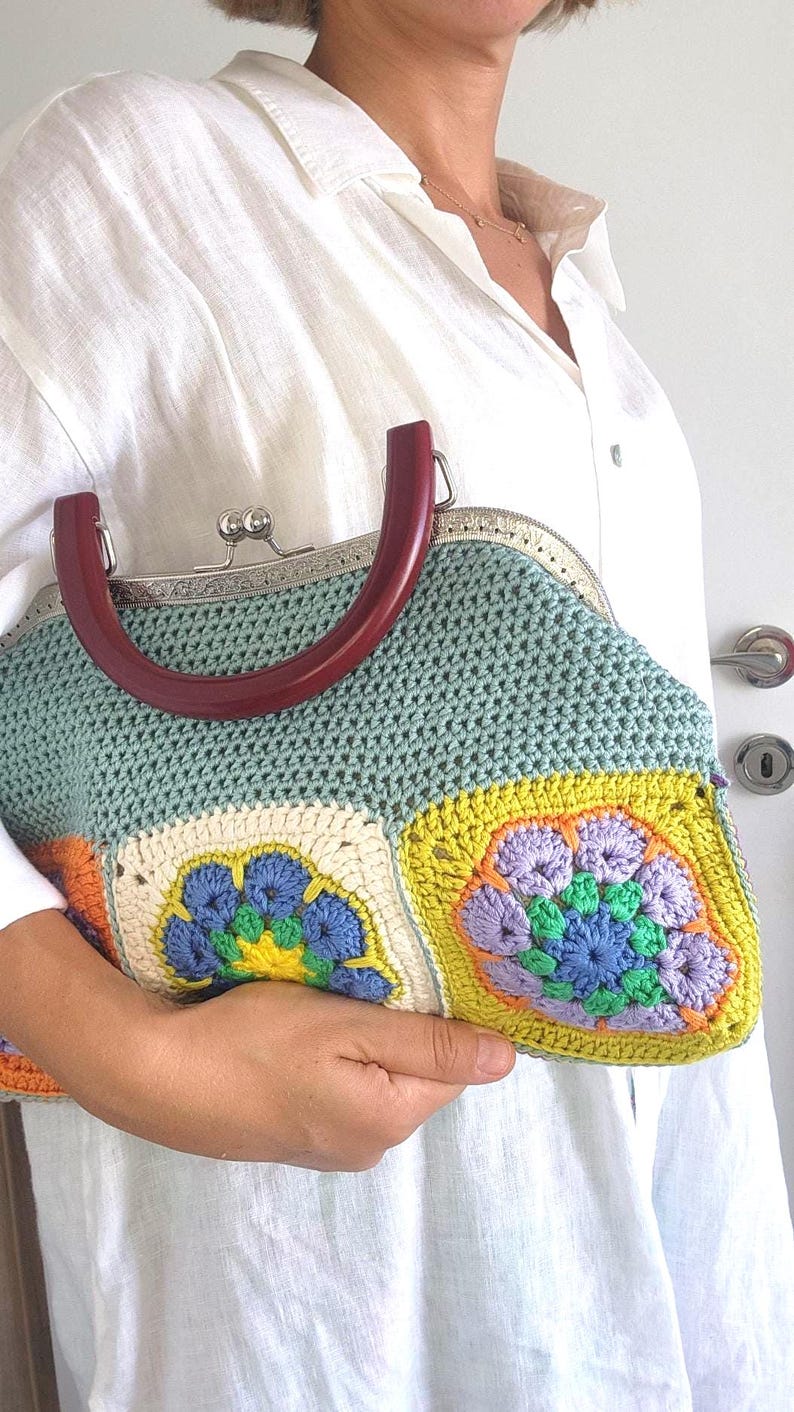 The bag is finished with a sturdy metal kiss lock clasp and elegant dark handles, making it perfect for both casual outings and special occasions.