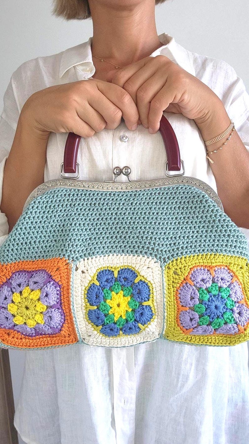 The bag is finished with a sturdy metal kiss lock clasp and elegant dark handles, making it perfect for both casual outings and special occasions.