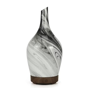 May include: An essential oil diffuser with a striking black and white marble effect. The diffuser has a wooden base and a distinctive angled top. The swirling pattern gives it a modern, artistic look. The base has control buttons.