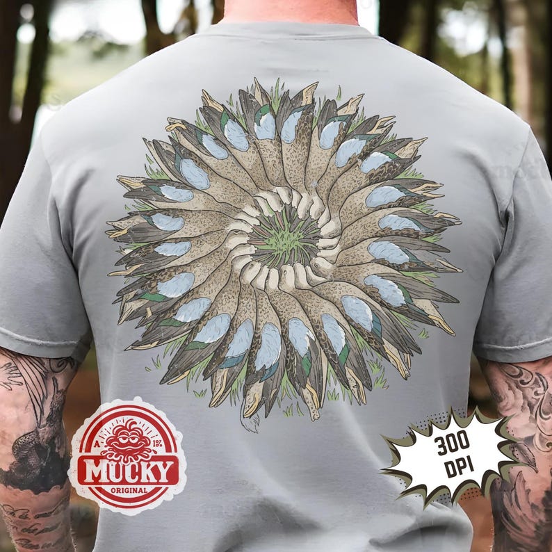 May include: Grey t-shirt with a circular duck design in shades of brown, blue, and green, centered on the back. The shirt includes a "Mucky Original" logo and a "300 DPI" graphic.