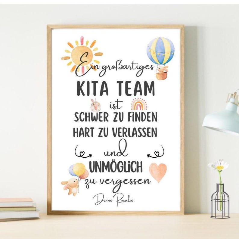 May include: A framed print with the text "Ein gro&szlig;artiges KITA TEAM ist SCHWER ZU FINDEN HART ZU VERLASSEN und UNM&Ouml;GLICH zu vergessen Deine Rosalie." The print features watercolor illustrations of a sun, hot air balloon, and teddy bear.