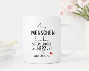 Puede incluir: Taza de cerámica blanca con un gráfico en blanco y negro que dice "Kleine Menschen brauchen so ein großes Herz wie deins" con un pequeño corazón rojo.