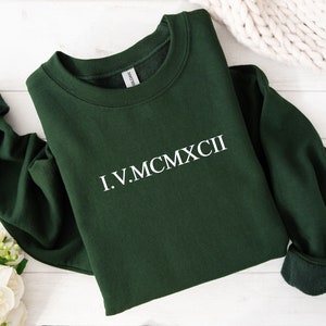 Roman numeral numbers in white in the centre of a green folded sweatshirt