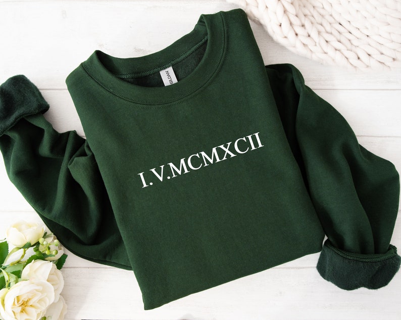 Roman numeral numbers in white in the centre of a green folded sweatshirt
