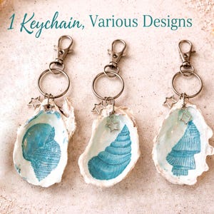 May include: Three keyrings with seashell pendants. Each pendant is a white seashell with a blue design and a silver star charm. The text "1 Keychain, Various Designs" is at the top.