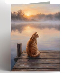 May include: A greeting card depicting an orange tabby cat on a wooden jetty, overlooking a misty lake at dawn. The painting uses a soft, painterly technique with warm colours, evoking a sense of peace.