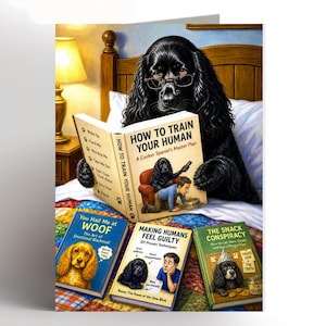 May include: A humorous greeting card depicting a black Cocker Spaniel wearing spectacles and reading a book titled "How to Train Your Human." Other books on the card have titles such as "You Had Me at WOOF" and "Making Humans Feel Guilty."