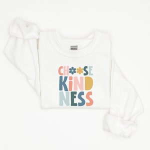May include: White long-sleeved sweatshirt with the text "Choose Kindness" in colourful block letters with flowers.