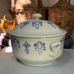 Peut inclure: Une soupière en céramique blanche avec couvercle, ornée d'un motif floral et géométrique bleu répétitif. Le récipient rond comprend deux anses latérales et un couvercle assorti avec un bouton central. Le design se compose de motifs bleus symétriques disposés autour de l'extérieur et du couvercle, offrant une apparence classique pour cette pièce de service.