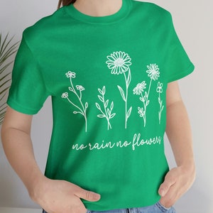 Peut inclure: Un t-shirt vert avec un motif blanc de fleurs et le texte "no rain no flowers".
